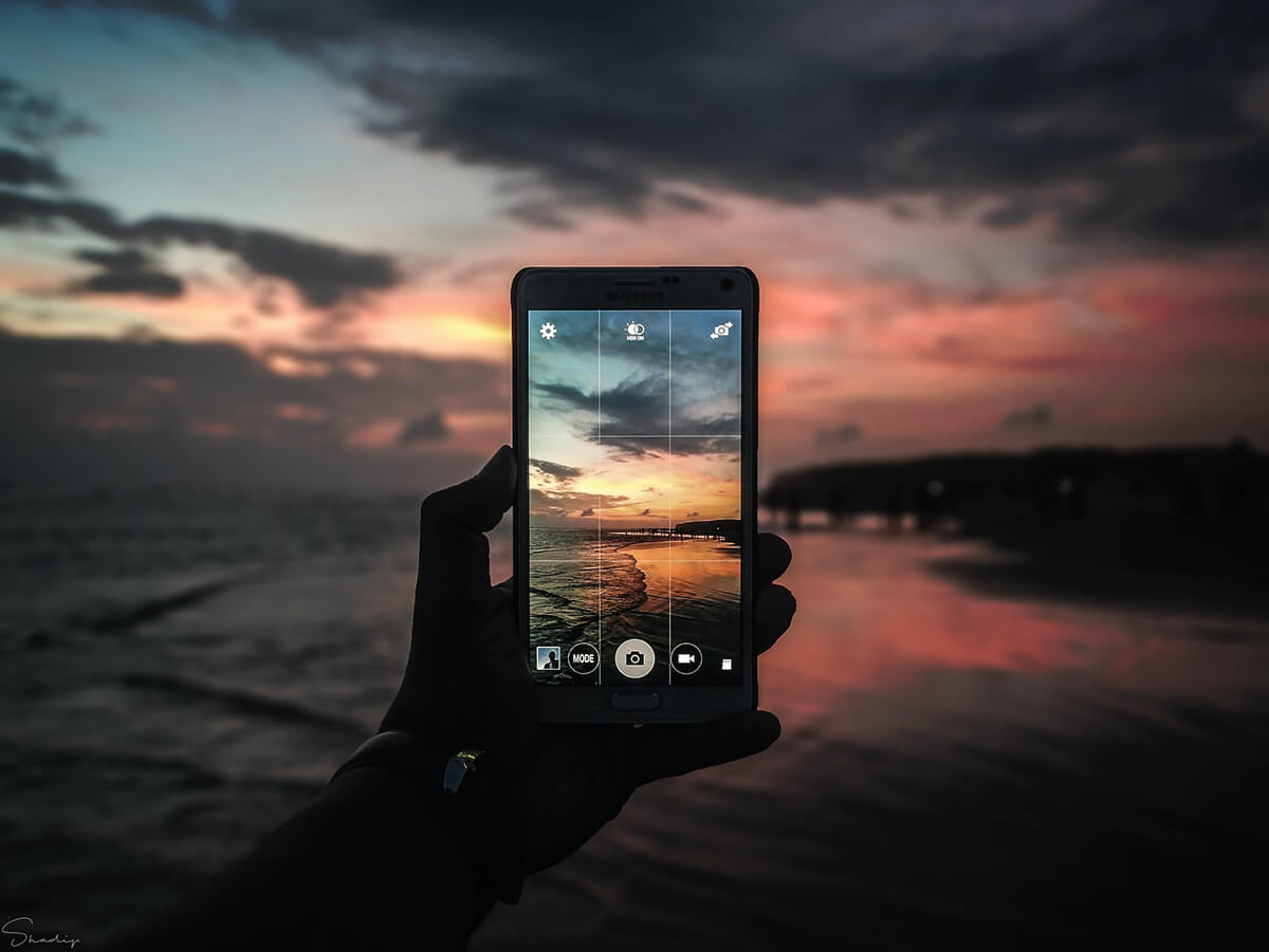 Person, die mit ihrem Telefon ein Sonnenuntergangsfoto macht